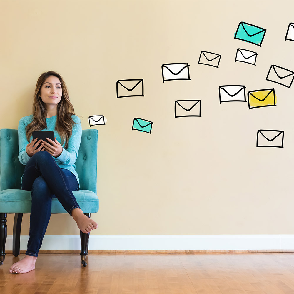 emails photo of a woman checking email on a couch