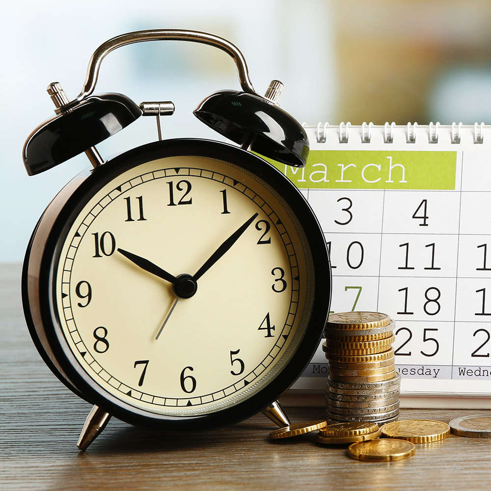 schedule photo of an alarm clock, coins, and a calendar on a table